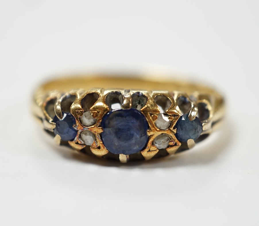 An early 20th century continental yellow metal (stamped 18) and three stone diamond set half hoop ring, with four stone diamond chip spacers, size O, gross weight 4.5 grams. Fair condition.